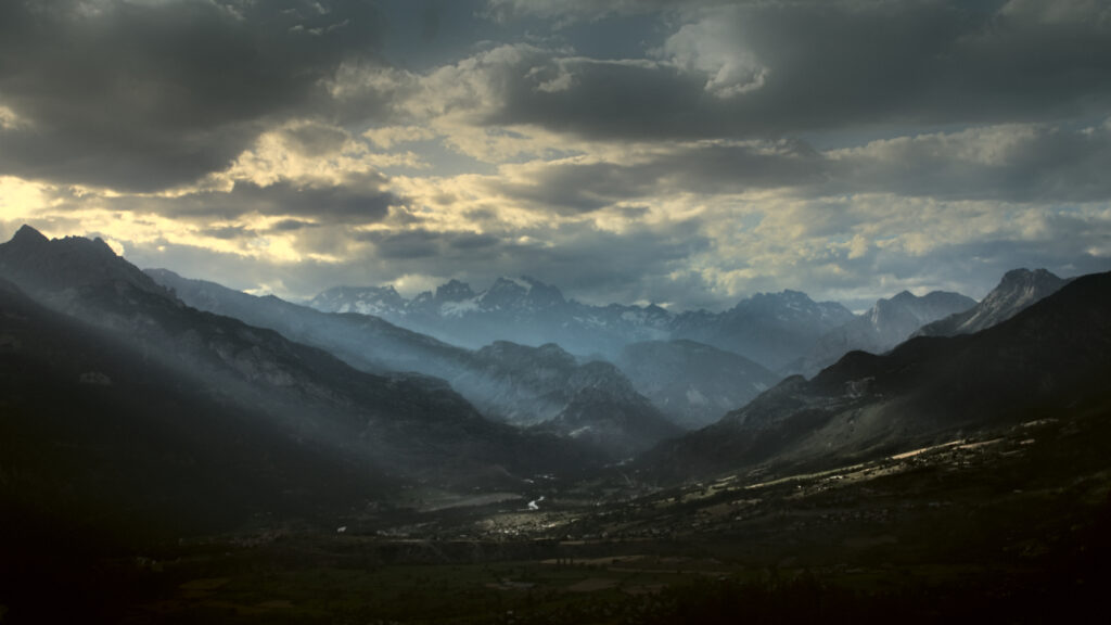 Twilight mountain landscape with dramatic clouds rays of light rugged peaks and serene valleys background Wallpaper