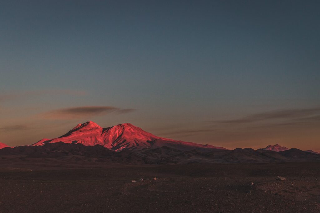 Mountain peak at twilight glowing warm orange fading to deep blue sky tranquil wallpaper background