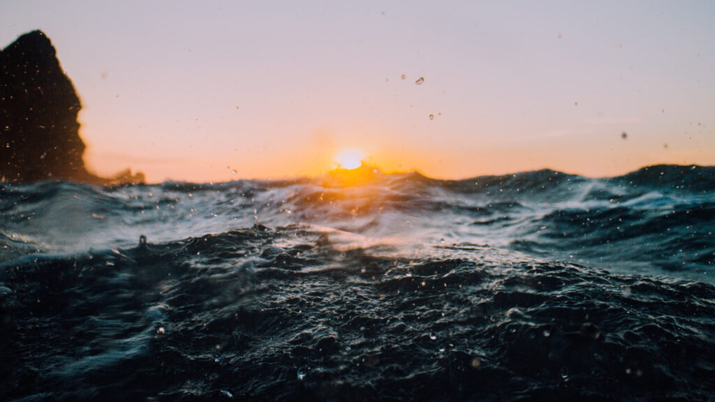 High resolution wallpaper of dynamic ocean waves at sunset with blue and golden hues droplets