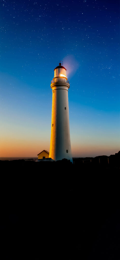 Twilight Glow: Mesmerizing Lighthouse Silhouette on Your Iphone Amoled - Perfect Background Wallpaper