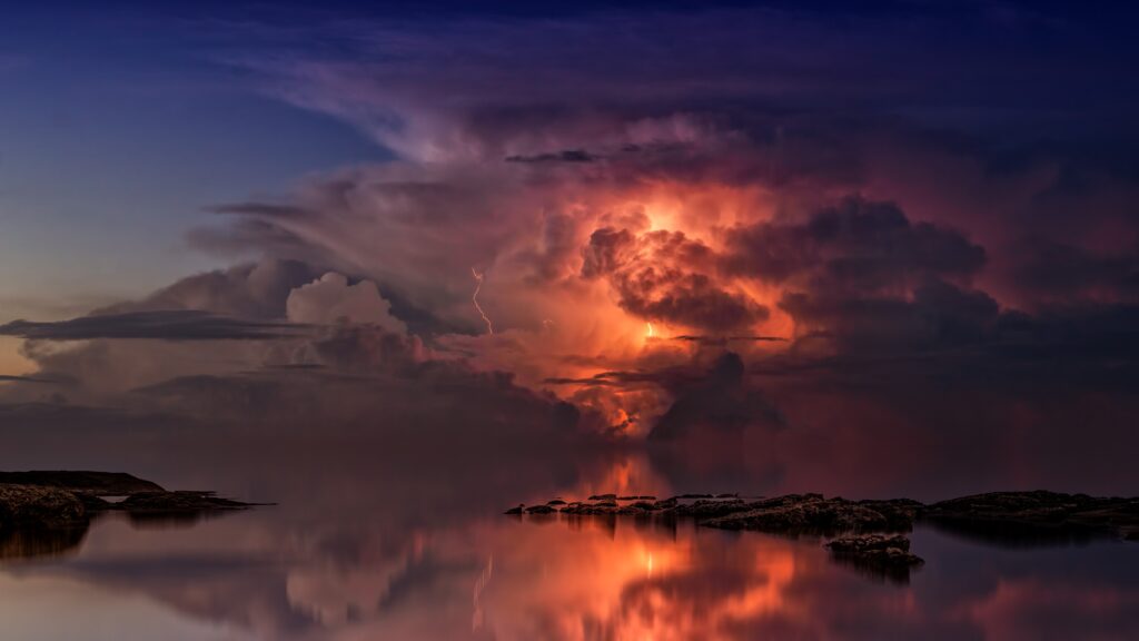 Thunderstorm over calm ocean coast at twilight with vivid lightning and glowing orange pink hues Wallpaper