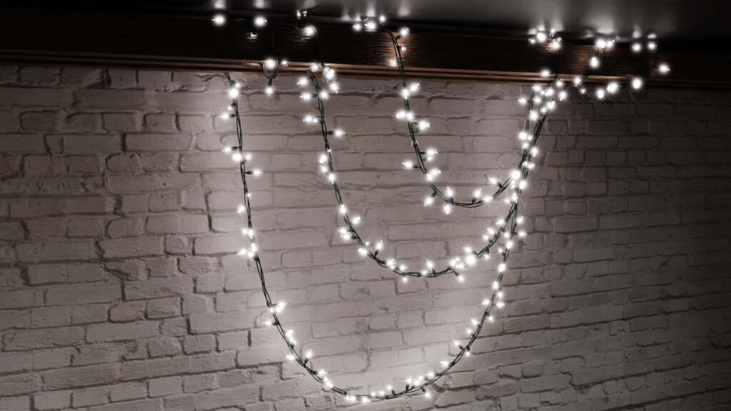 Twinkling String Lights on White Brick Wall: Festive Holiday Ambiance Wallpaper