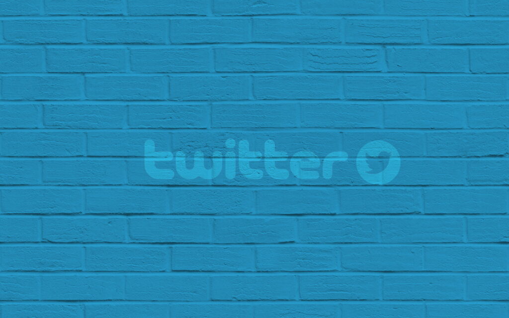 Twitter's Iconic Logo Gracefully Adorns a Striking Brick Wall: A QHD Wallpaper Background