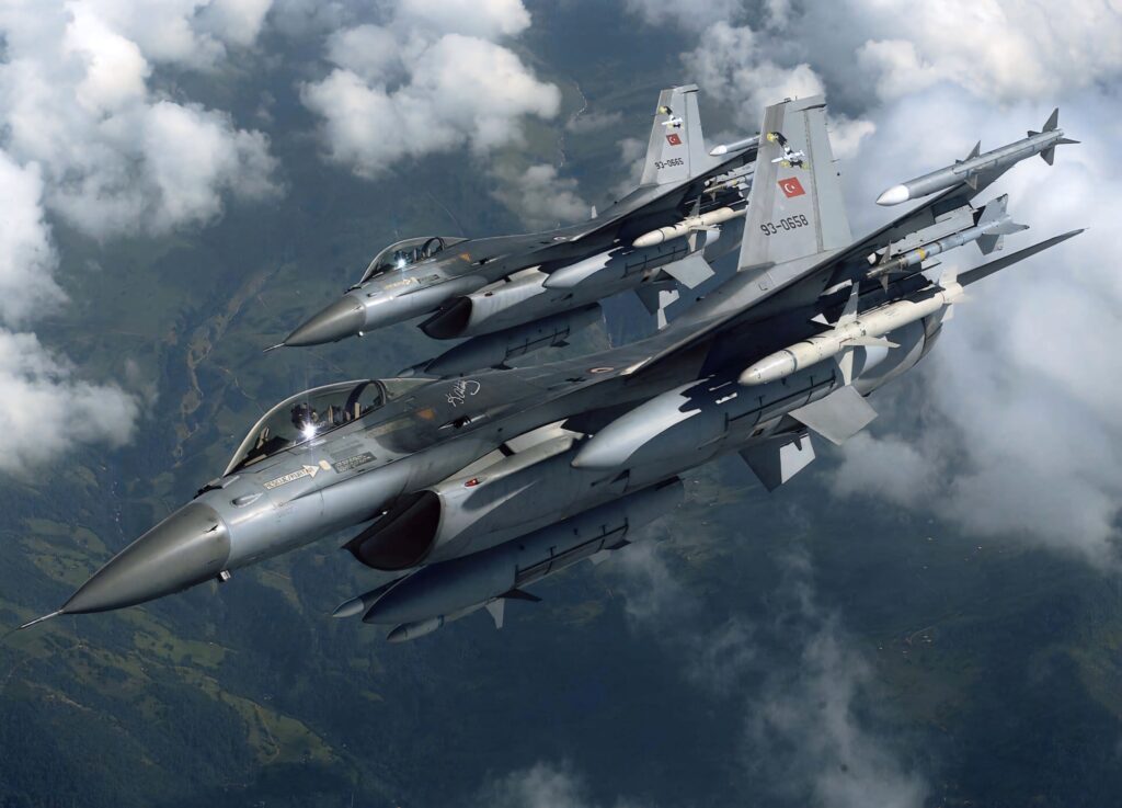 Two General Dynamics F-16 jets fly tight formation above clouds showcasing sleek design and camouflage Wallpaper