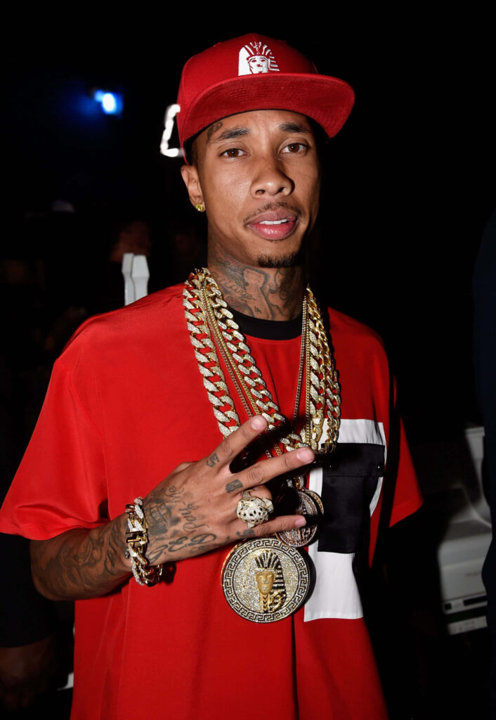 Tyga's Confident Style: Gold Chain & Red Attire Wallpaper Background