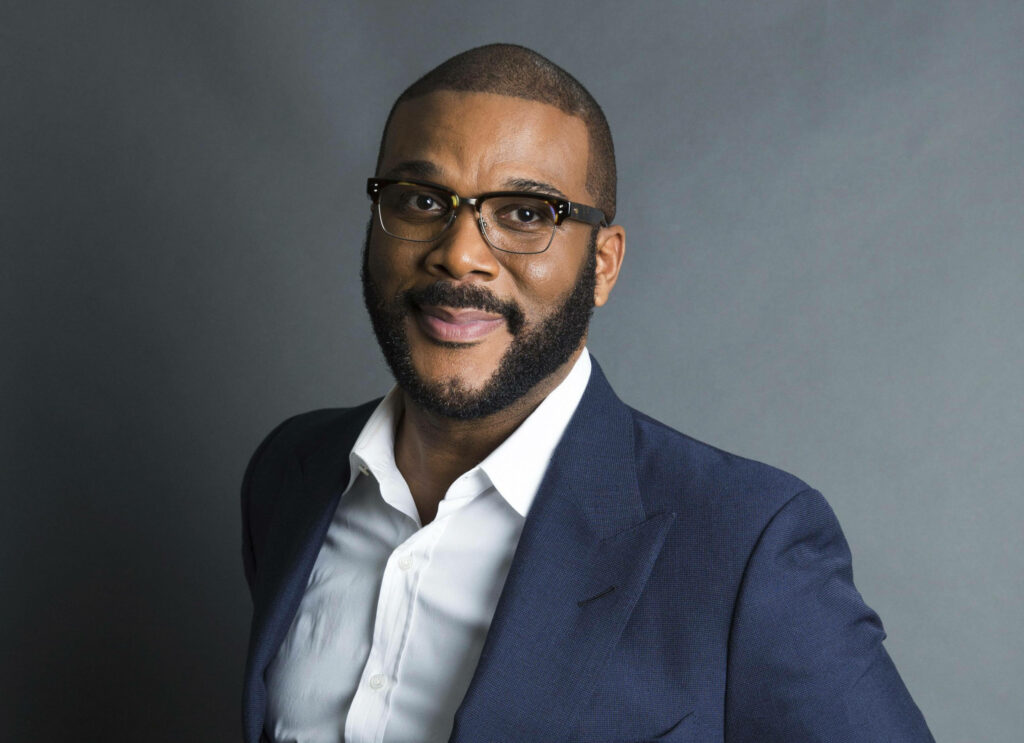 Tyler Perry in a sharp suit with beard and glasses against grey background professional portrait Wallpaper