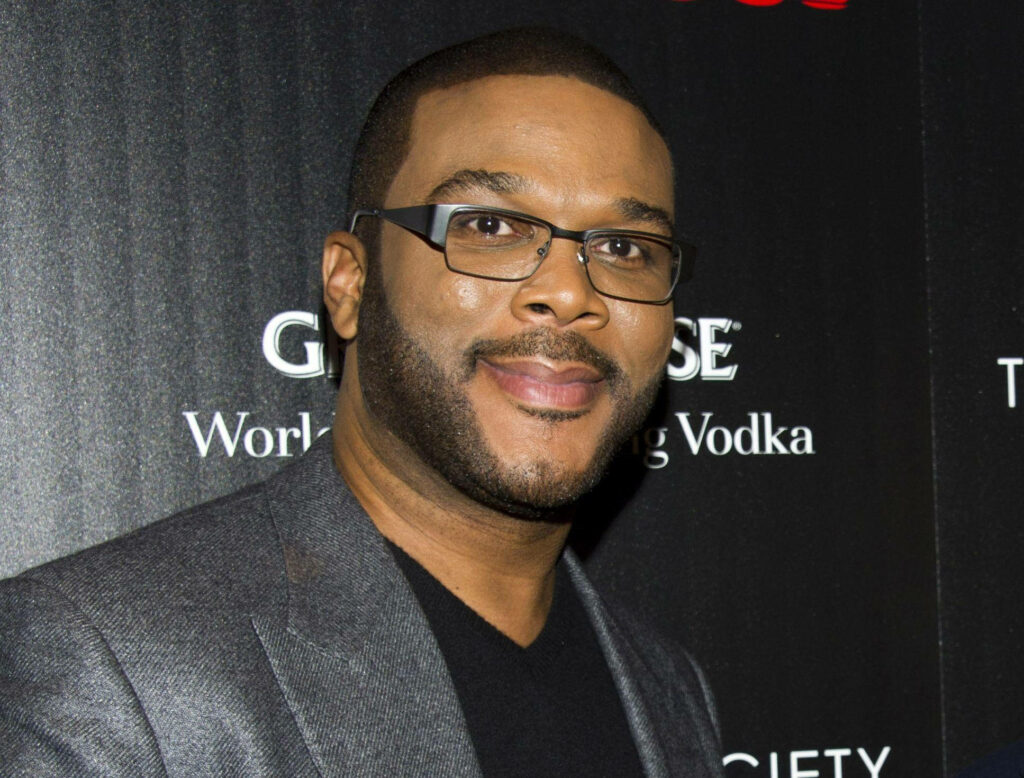 Tyler Perry confident in stylish grey suit and glasses posing on red carpet wallpaper background