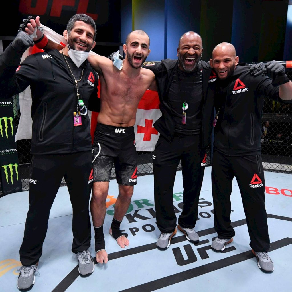 UFC fighter Giga Chikadze celebrating victory inside Octagon with team and Georgian flag Wallpaper