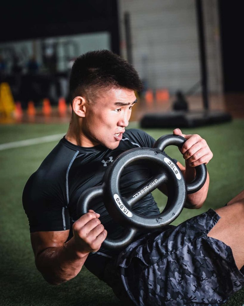 UFC fighter Song Yadong intense ab workout on gym turf with 35lb Gripbell and Under Armour Wallpaper