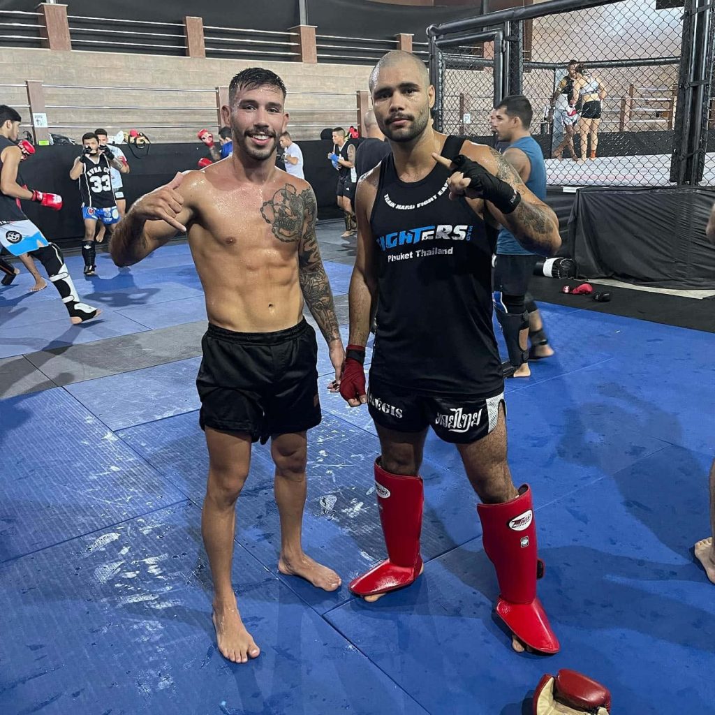 UFC flyweight Matheus Nicolau training shirtless with teammate in MMA gym cage background Wallpaper