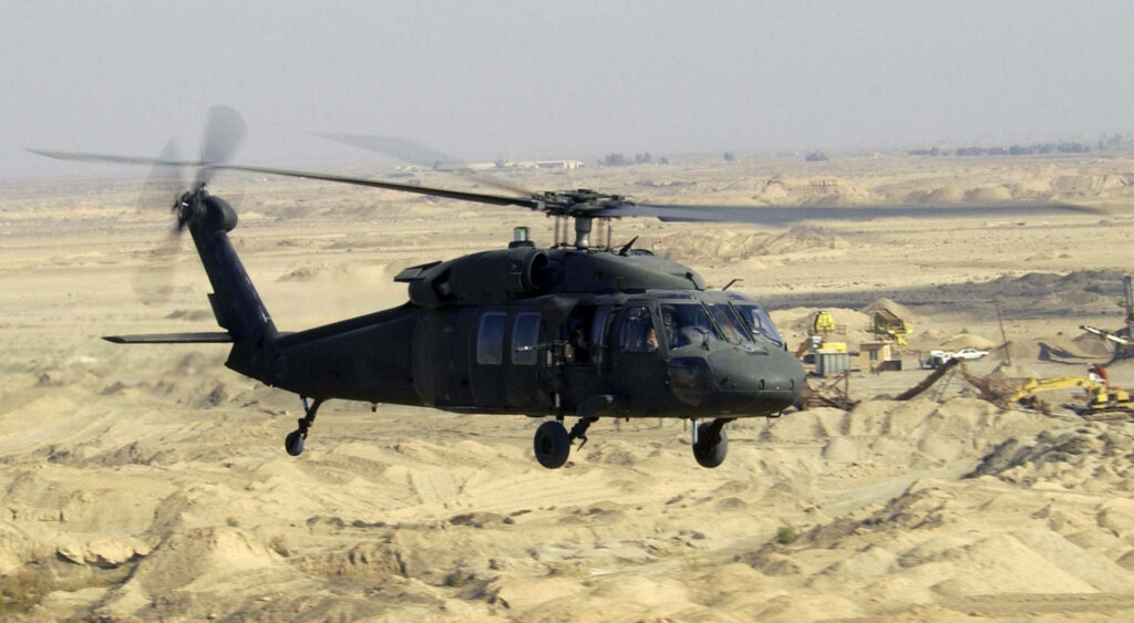 UH-60L Black Hawk helicopter flying low over rugged desert terrain showing military power Wallpaper