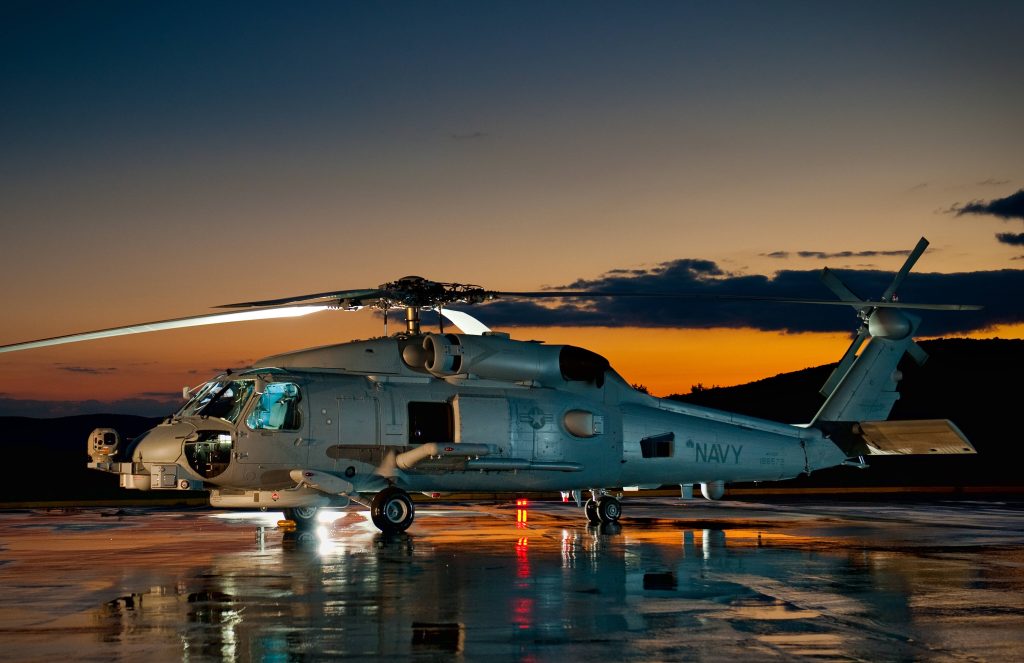 US Navy MH-60 Seahawk helicopter on reflective tarmac at twilight with vibrant sunset sky Wallpaper