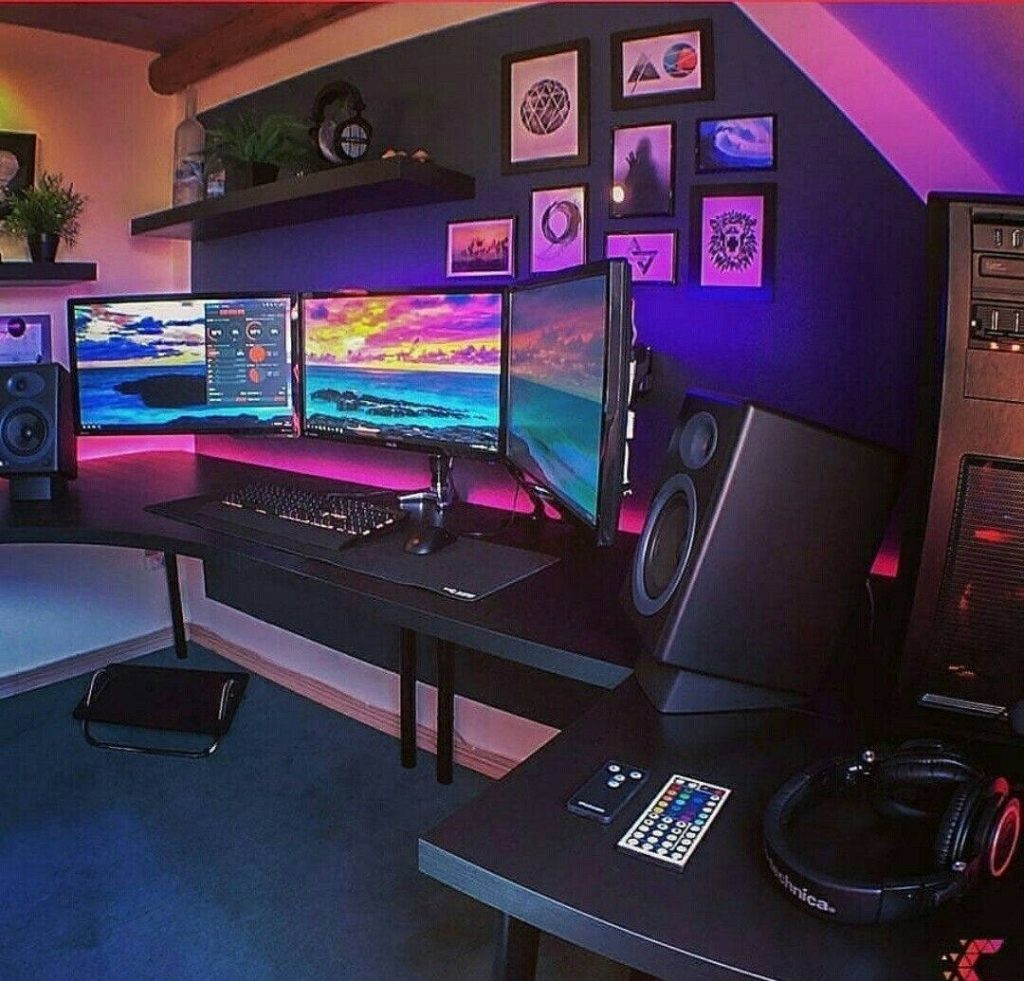 Triple monitor gaming setup wallpaper with neon purple and pink lighting and sleek desk