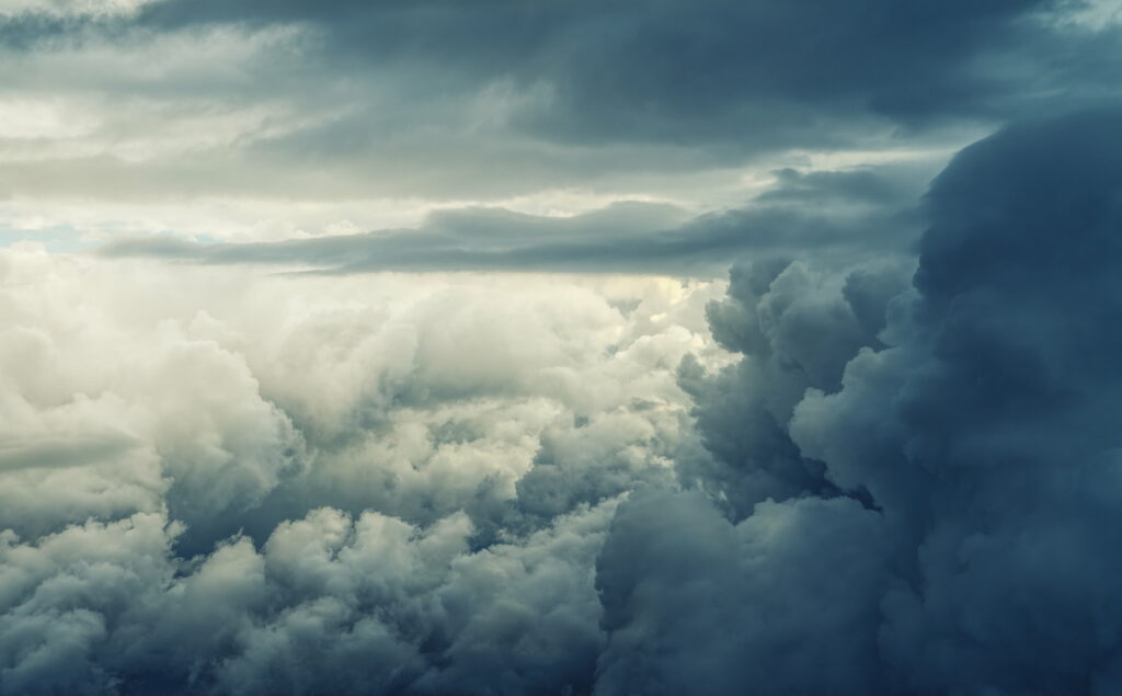Panoramic high-altitude sky with dark storm clouds and bright sunlit fluffy clouds wallpaper
