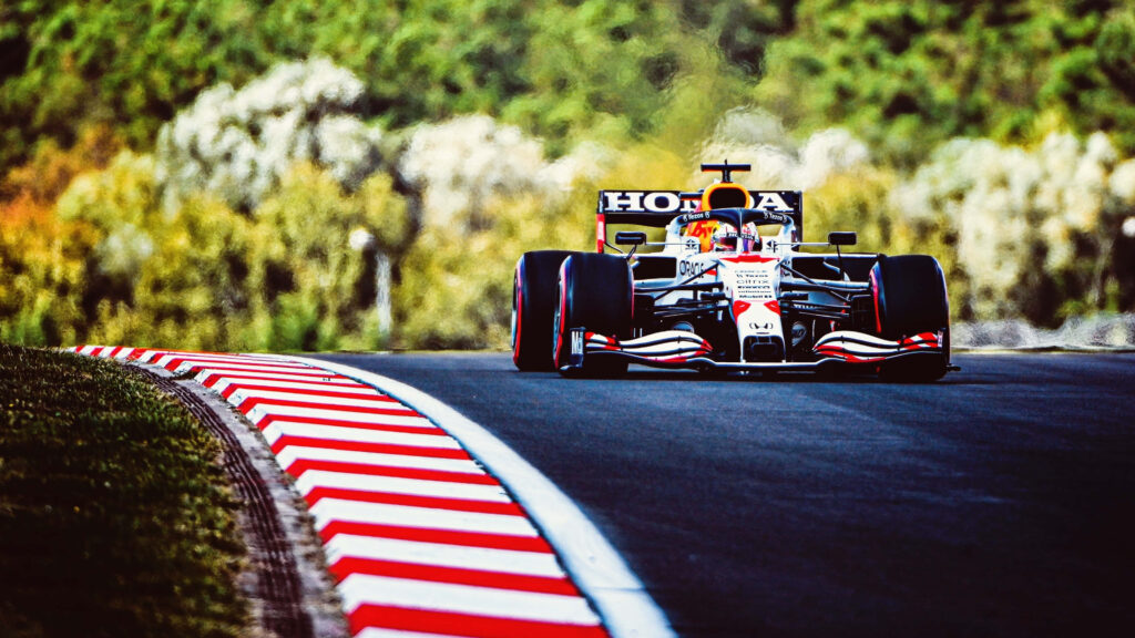 Ultra wide 4K Formula 1 car racing sharp curve vibrant green landscape high speed wallpaper background