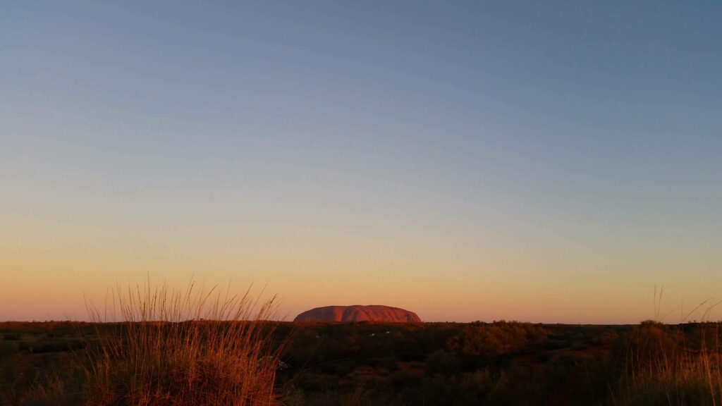 Uluru at sunset in the Australian Outback with clear sky serene natural landscape wallpaper background