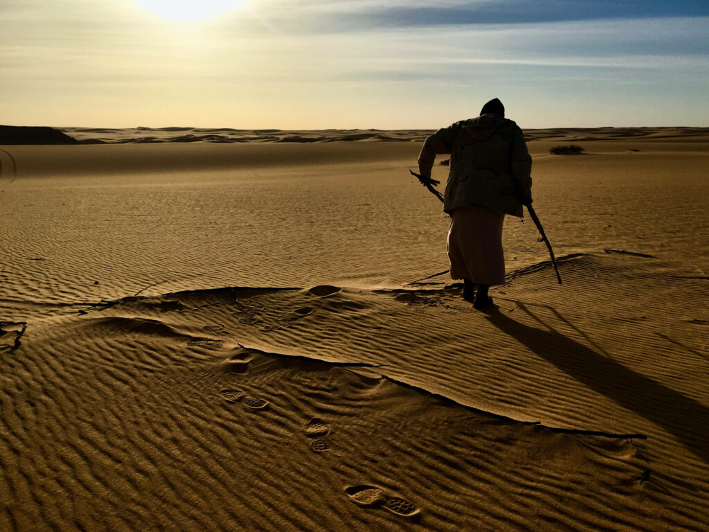 Man trekking alone through arid Libyan landscape Wallpaper