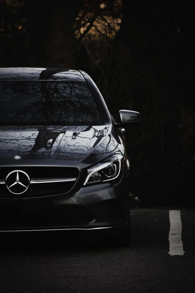 Under the Shade: A Sleek Mercedes Benz Rests Amidst Nature's Canopy Wallpaper