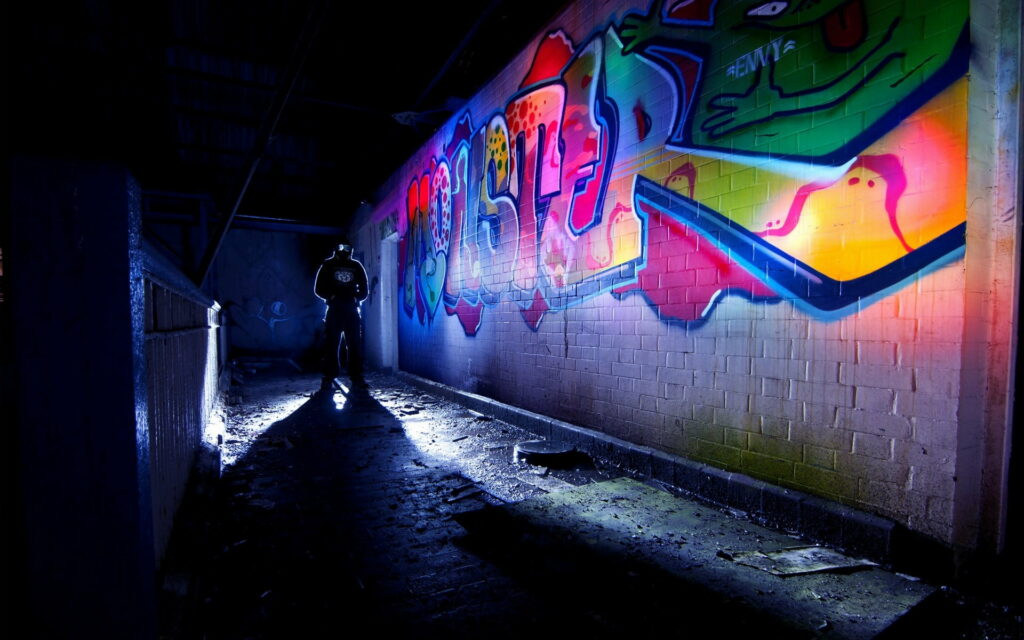 The Urban Artistry Unleashed: A Vibrant Mural on the Shadowed Underground Wall Wallpaper