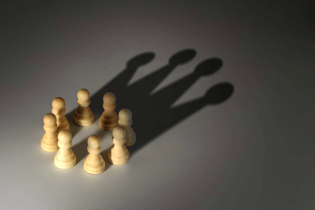 Wooden pawns in circle casting queen shadows symbolizing unity and empowerment against racism Wallpaper