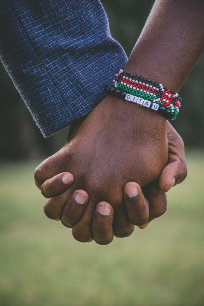 Intertwined Love: Couple's Hands Grasping, Adorned with Beaded Bracelets Wallpaper