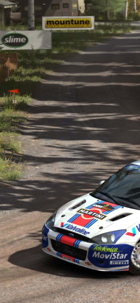High-speed rally car kicking up dust on gravel road in wooded area for motorsport enthusiasts Wallpaper