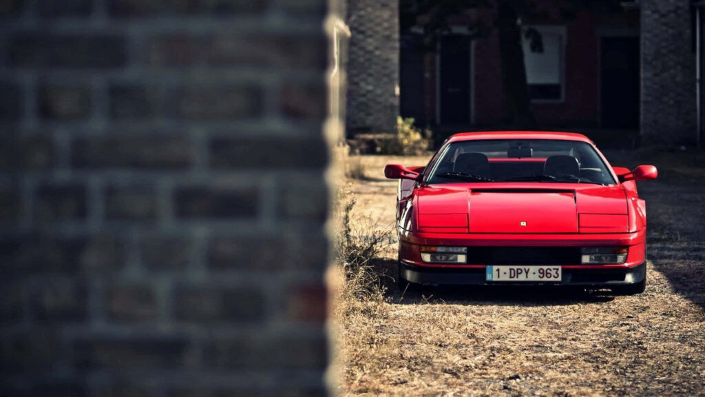 Red Ferrari Testarossa Near a Brick Wall Background Wallpaper