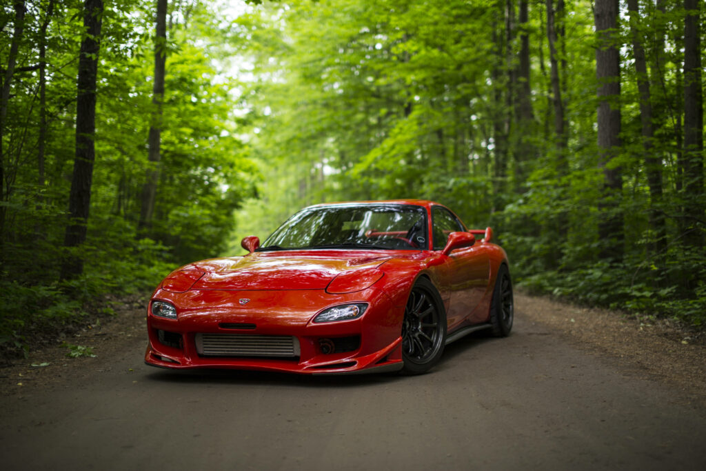 Immersed in Nature: Striking Rx7 Poses Gracefully amidst Enchanting Woods Wallpaper