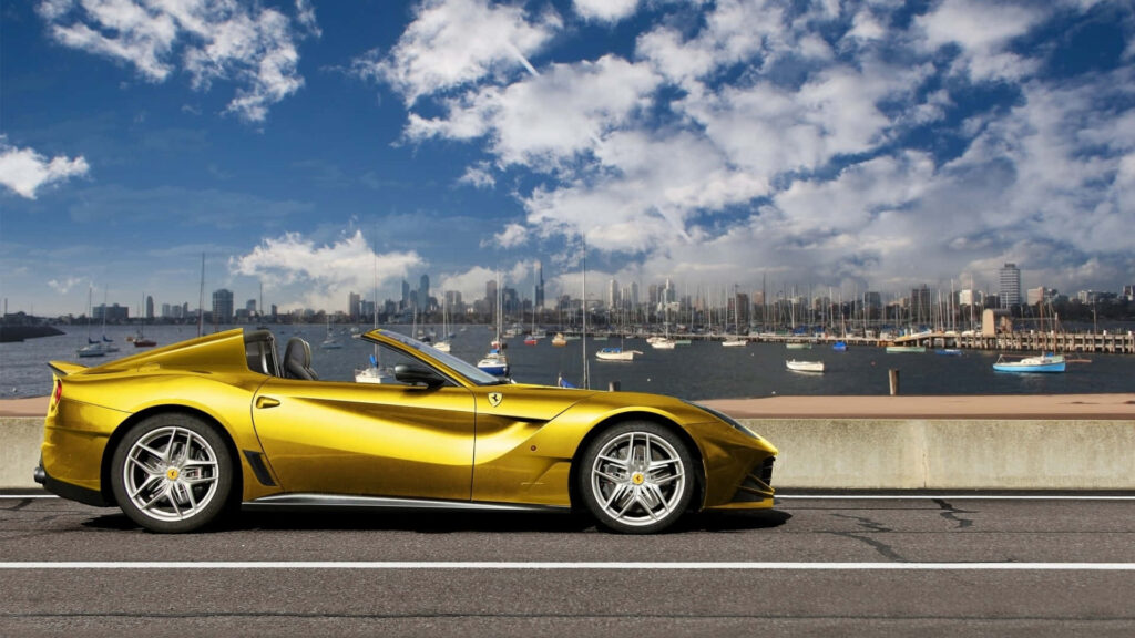 Gold Ferrari F12 Berlinetta against a Cityscape Background Wallpaper
