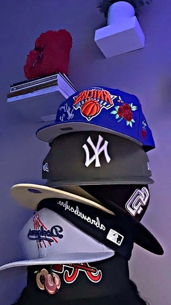 Stacked trendy baseball caps New York Knicks Yankees purple moody lighting urban streetwear wallpaper