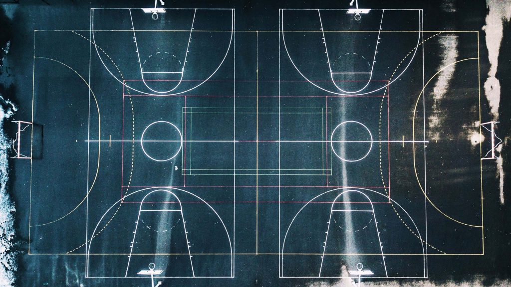 Aerial view of urban basketball court with geometric markings and vertical light streaks Wallpaper