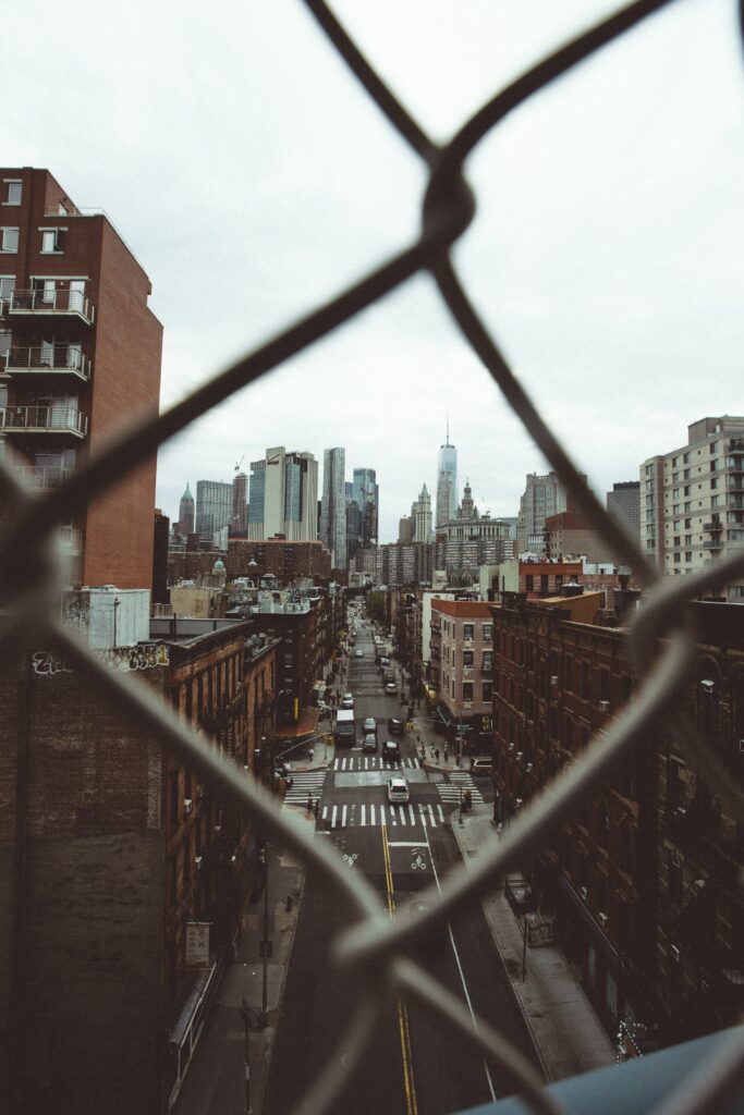Aerial Cityscape Wallpaper: Urban View Through Chain-Link Fence