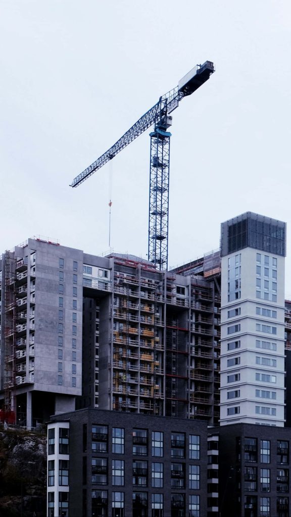 Urban construction site with tower crane concrete building modern high-rise skyline background Wallpaper