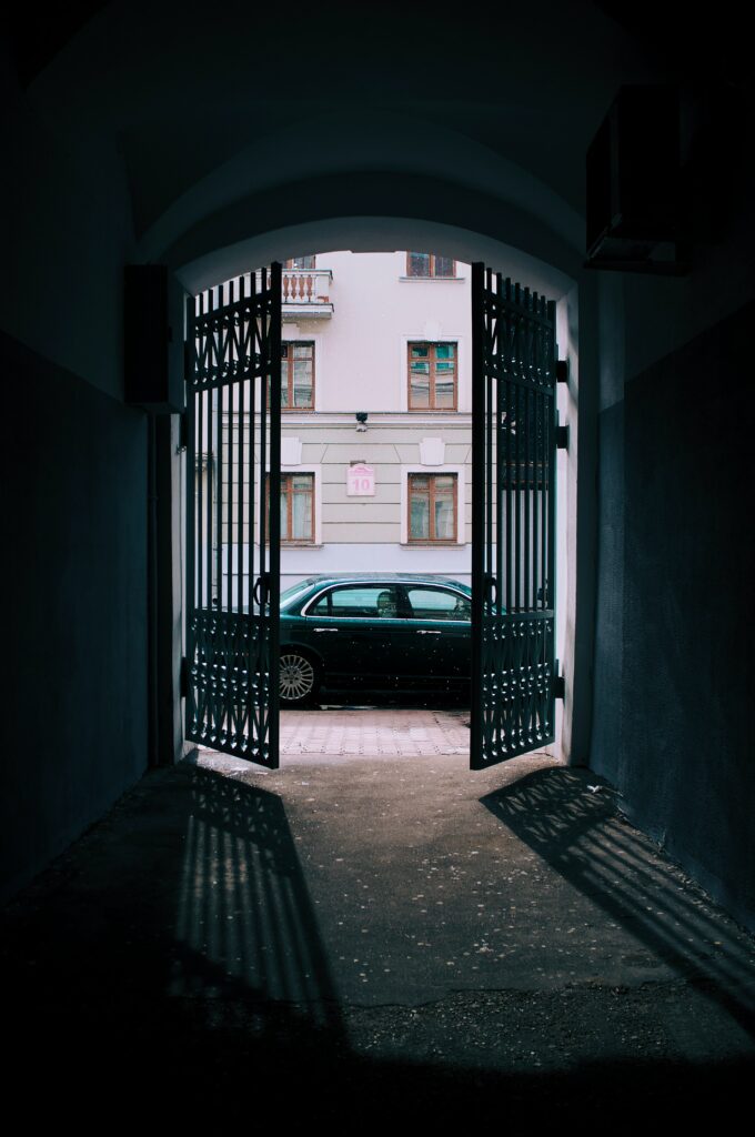 Black Car by Wrought Iron Gate: Urban Scene with Classic Building Wallpaper