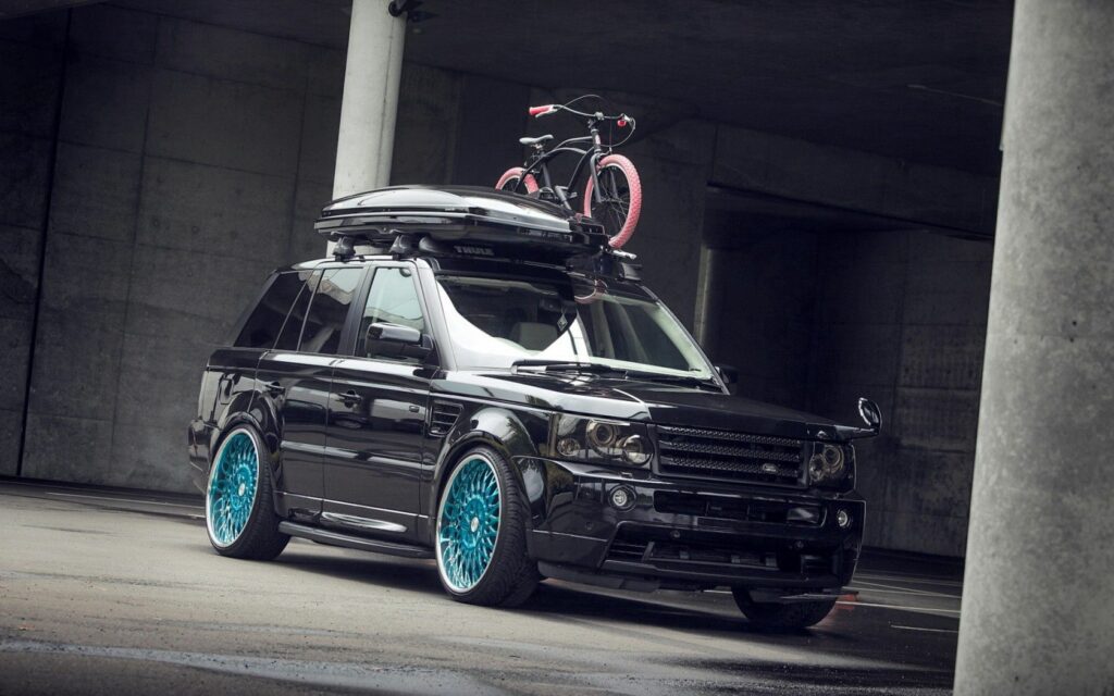 Sleek Black Land Rover with Blue Rims in Urban Setting - Adventure Ready Wallpaper
