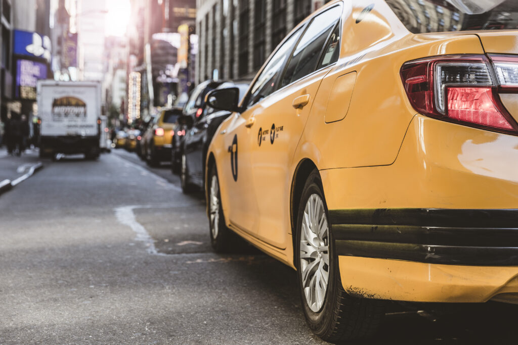 Urban Yellow Taxi Wallpaper: Detailed Headlight & Bustling City Scene