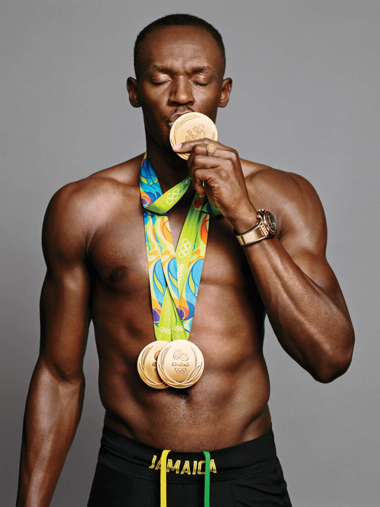 Usain Bolt shirtless kissing Olympic gold medal with multiple medals celebrating athletics success Wallpaper