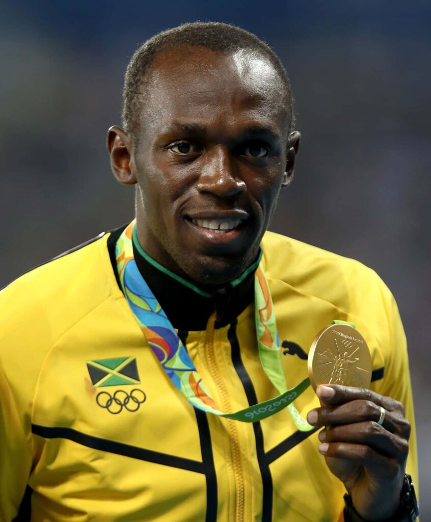 Usain Bolt smiling proudly holding gold medal wearing Jamaican track jacket vibrant wallpaper