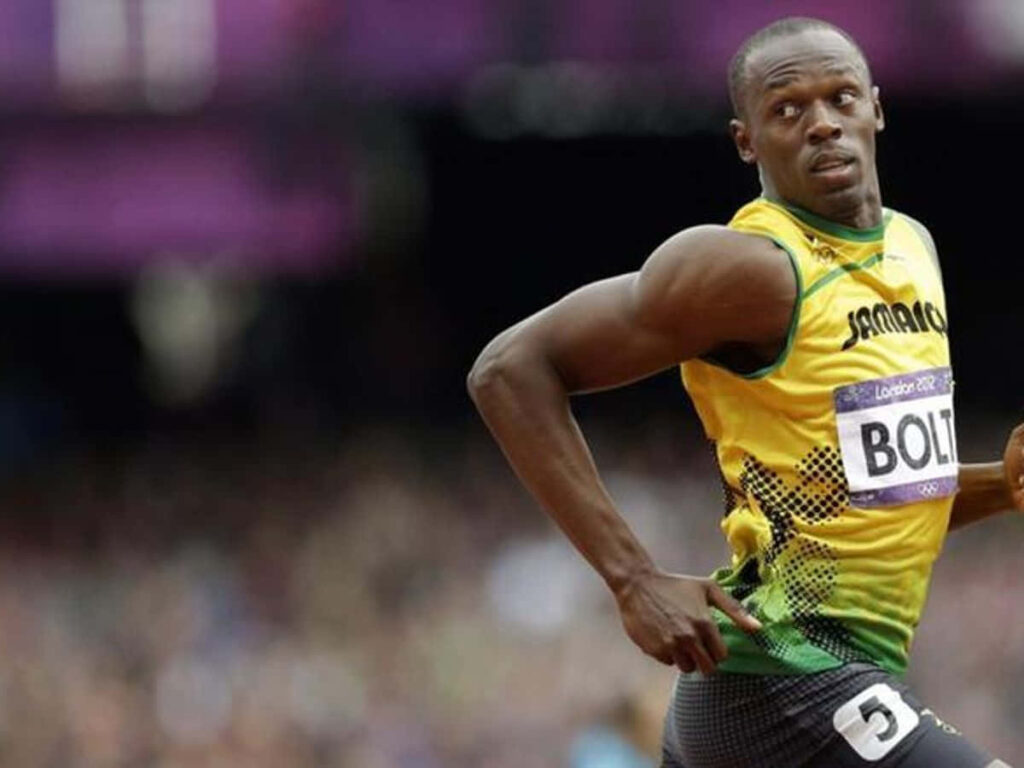 Usain Bolt sprinting on track in Jamaican uniform looking back showing legendary speed and dominance Wallpaper