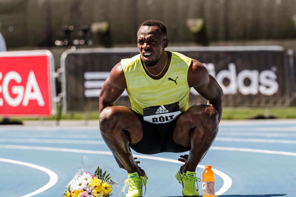 Usain Bolt stretching on track focused and ready to run dynamic athletic wallpaper background