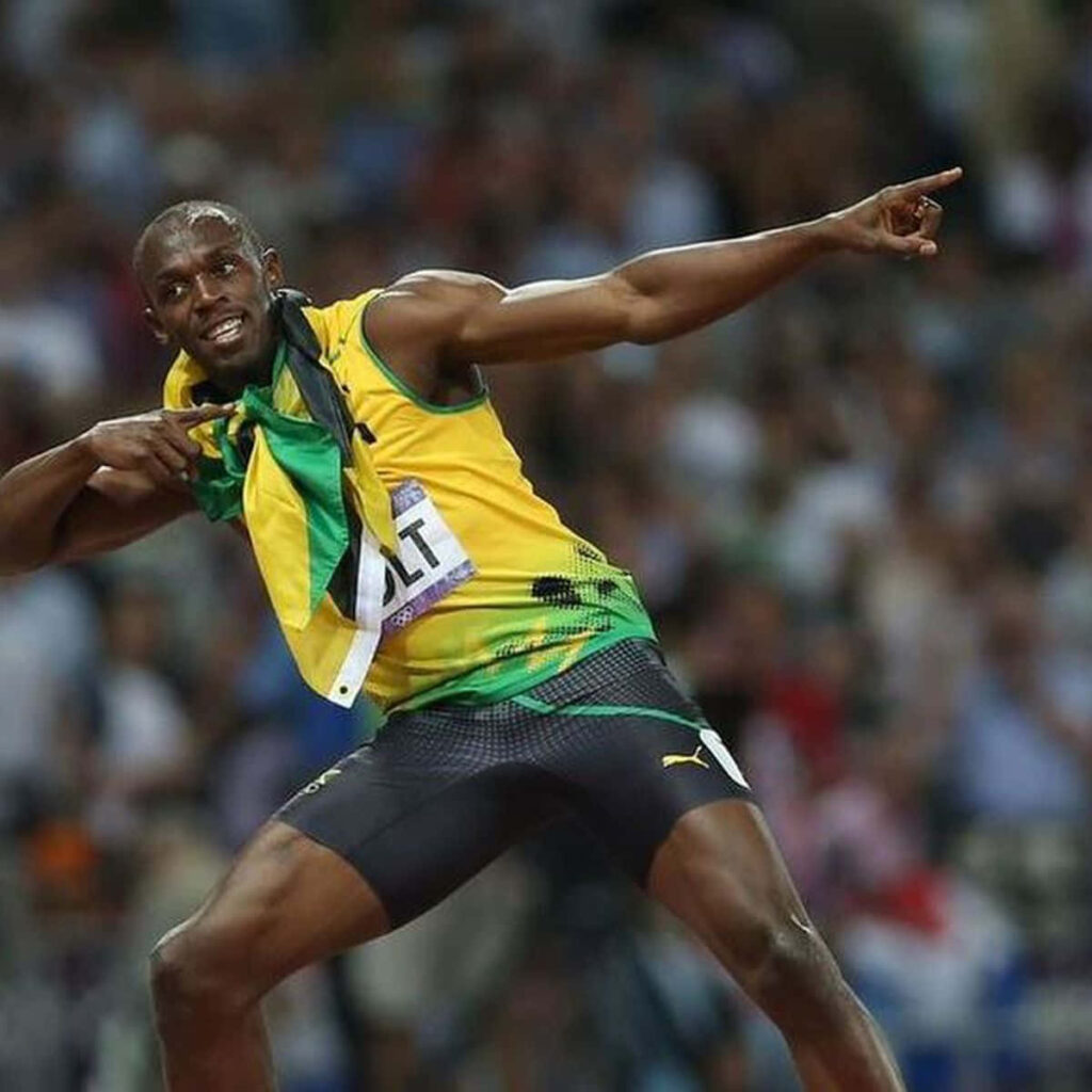 Usain Bolt celebrating victory on track with Jamaican flag in dynamic sports wallpaper background