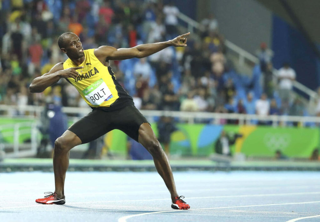Usain Bolt celebrates with iconic victory pose on track at major athletic event wallpaper background