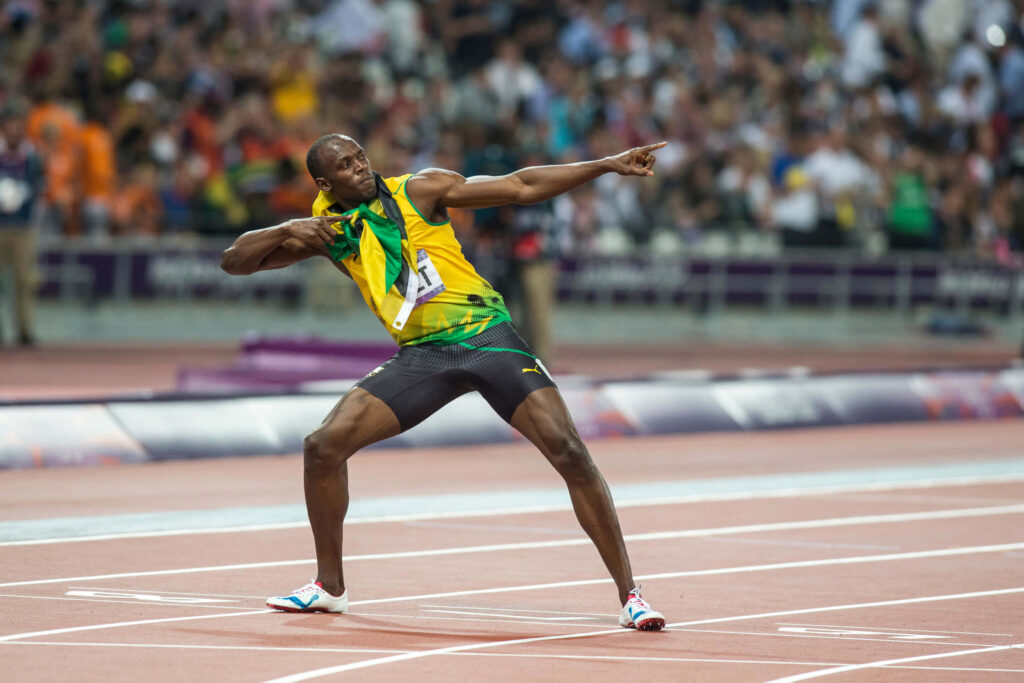 Usain Bolt in yellow green uniform striking victory pose on track celebrating iconic sprint win Wallpaper