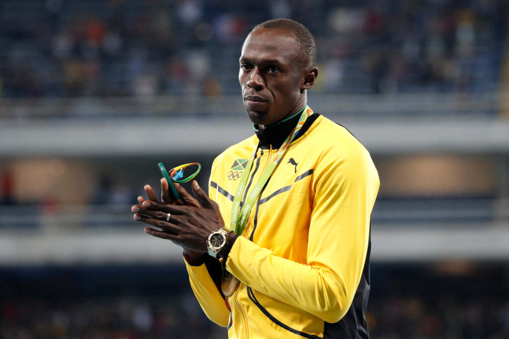 Usain Bolt in yellow jacket displaying medals iconic sprinter wallpaper background for fans
