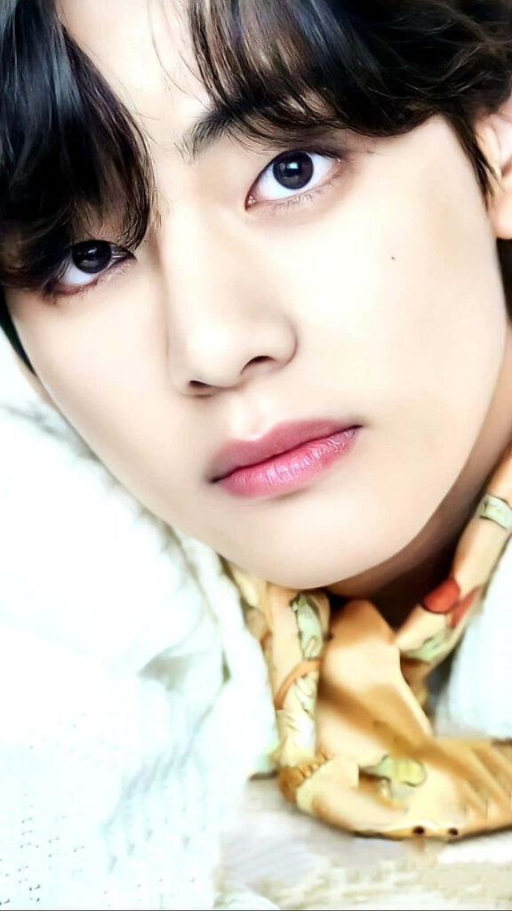 Close-up of V BTS with expressive eyes and soft lighting stylish charming mobile wallpaper background