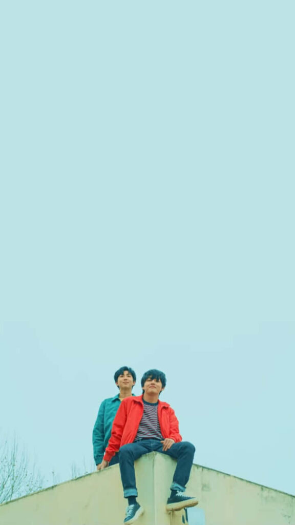 V BTS phone wallpaper with V seated on building edge under serene sky calm stylish background