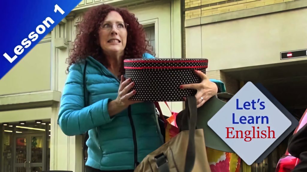 VOA Learning English host Jennifer Werner in teal jacket holding polka dot box teaching language Wallpaper