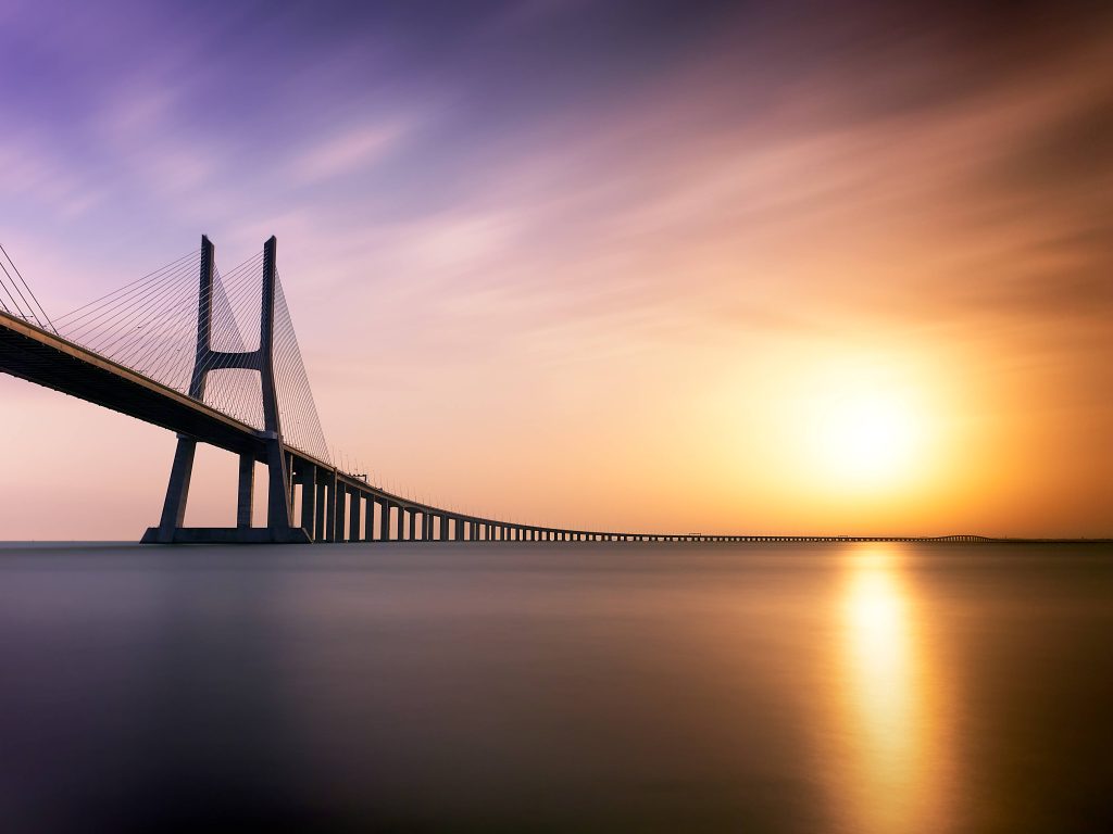 Vasco da Gama Bridge Lisbon sunset HD wallpaper golden light purple sky calm water view