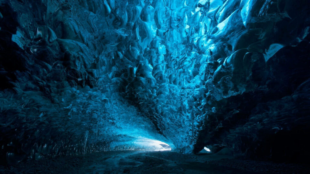 Stunning blue ice cave with sapphire ice formations glowing in ethereal natural light wallpaper