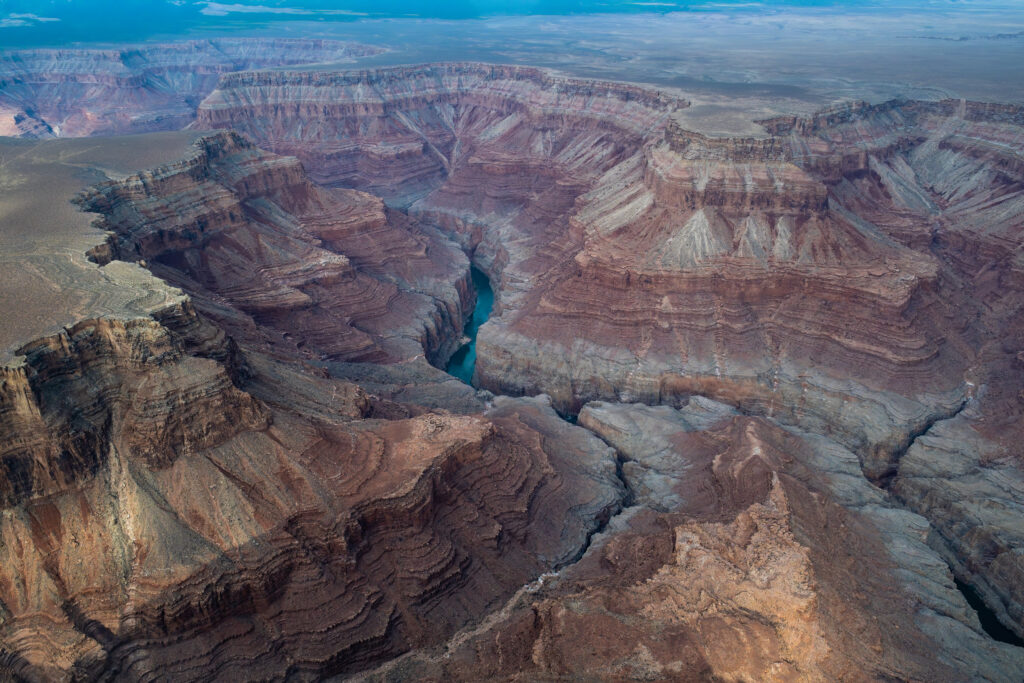 Vast canyon landscape with layered red rocks winding river and clear blue sky wallpaper background